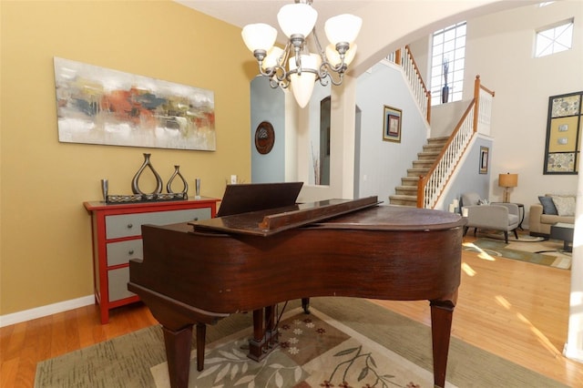 sitting room with stairway, wood finished floors, baseboards, arched walkways, and a chandelier