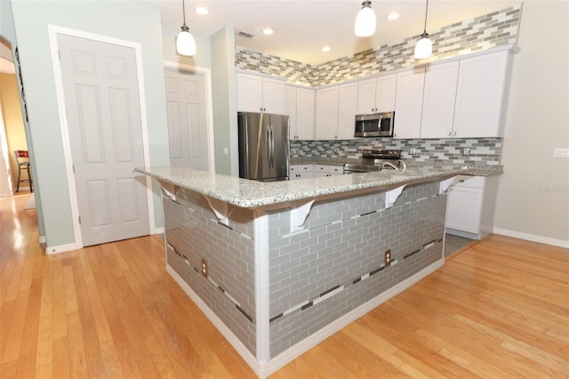 kitchen with stainless steel appliances, a kitchen bar, tasteful backsplash, and light wood finished floors