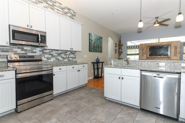 kitchen with backsplash, appliances with stainless steel finishes, hanging light fixtures, a ceiling fan, and a sink