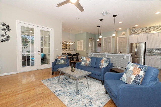 living room with visible vents, recessed lighting, french doors, ceiling fan with notable chandelier, and light wood-type flooring