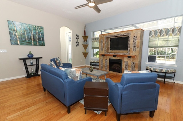 living area featuring a wealth of natural light, light wood-style flooring, arched walkways, and ceiling fan