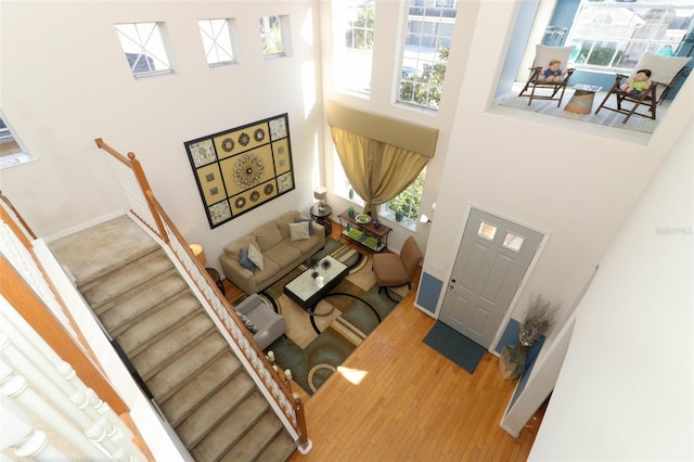 entrance foyer featuring stairs, wood finished floors, baseboards, and a towering ceiling