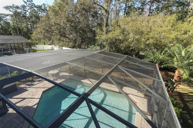 pool with a lanai, fence, and a patio