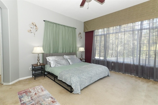 carpeted bedroom featuring arched walkways, a ceiling fan, and baseboards