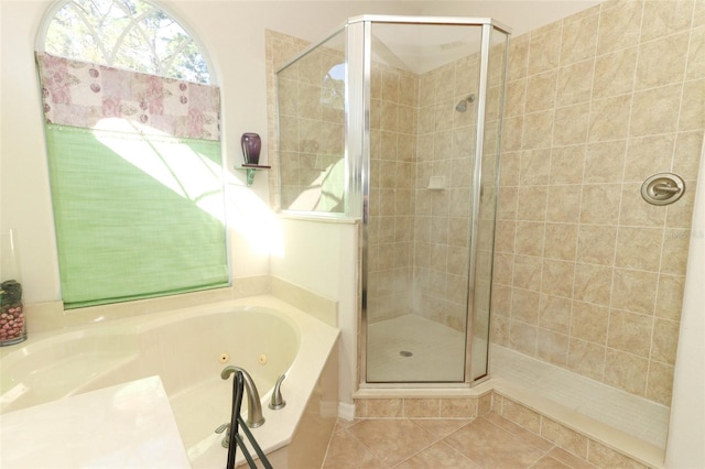 bathroom featuring tile patterned flooring, a tub with jets, and a stall shower