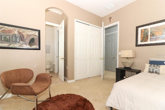 bedroom with baseboards, visible vents, a closet, ensuite bathroom, and light carpet