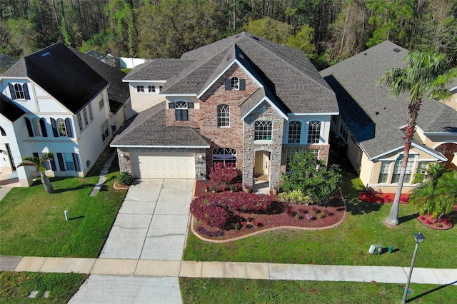 view of front of home featuring a front yard, an attached garage, concrete driveway, stone siding, and a view of trees