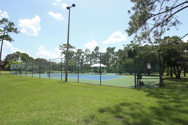 view of sport court featuring fence and a lawn