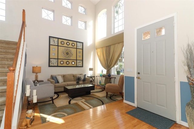 foyer entrance featuring stairs, wood finished floors, baseboards, and a towering ceiling