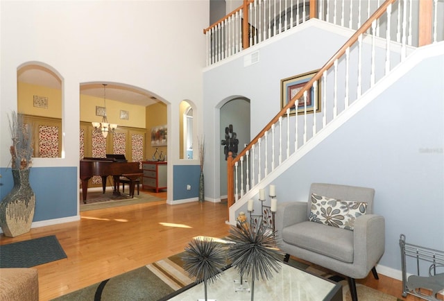 living room featuring wood finished floors, visible vents, baseboards, arched walkways, and stairs