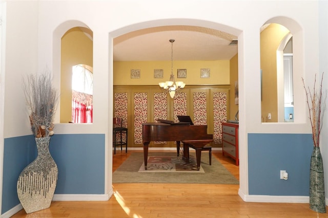 interior space featuring a notable chandelier, wood finished floors, and arched walkways