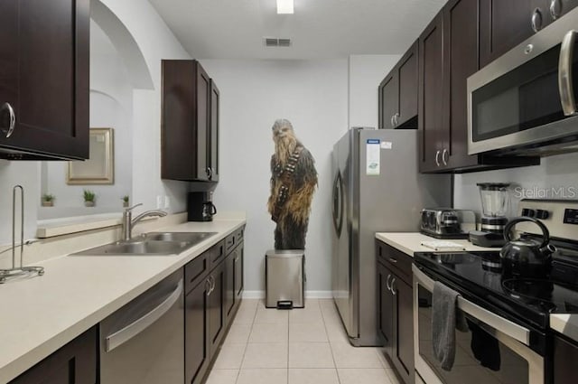 kitchen featuring visible vents, dark brown cabinetry, light countertops, stainless steel appliances, and a sink