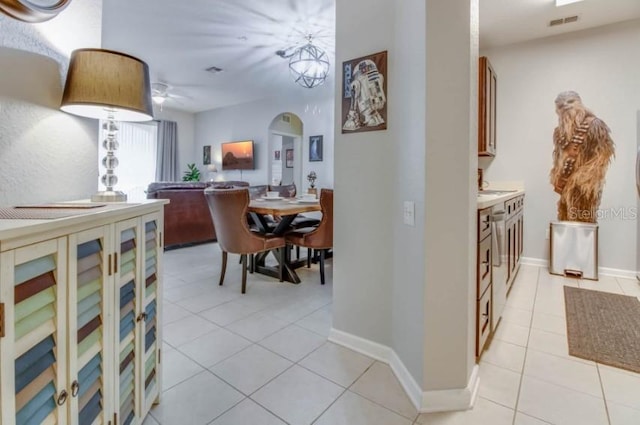 corridor featuring arched walkways, light tile patterned floors, baseboards, and visible vents