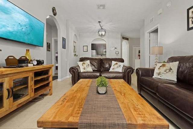 living area featuring arched walkways, visible vents, and light tile patterned floors