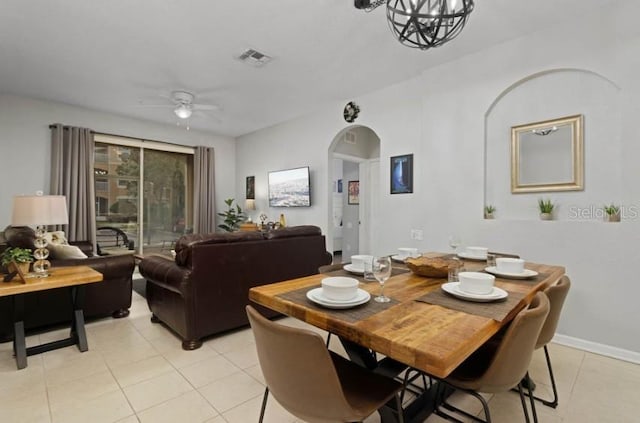 dining space featuring visible vents, arched walkways, light tile patterned flooring, and ceiling fan with notable chandelier