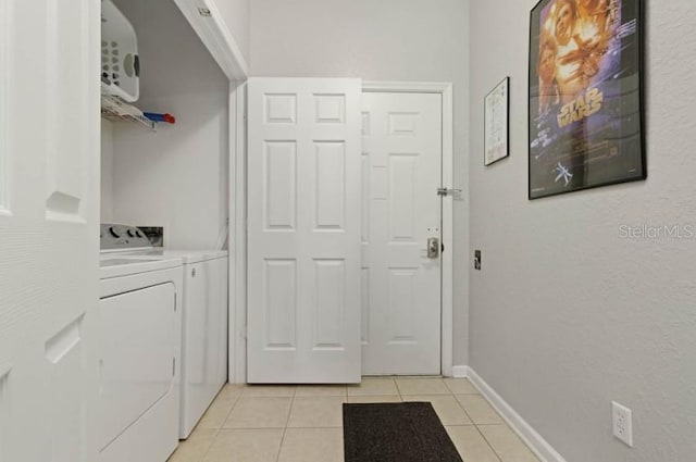 washroom featuring washing machine and clothes dryer, light tile patterned floors, and baseboards