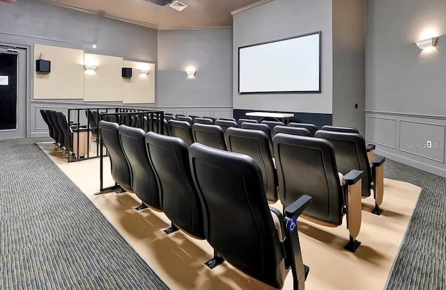 carpeted cinema room with wainscoting, crown molding, and a decorative wall