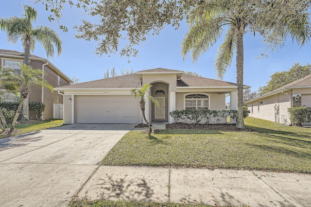 view of front of house with stucco siding, a front yard, an attached garage, and driveway