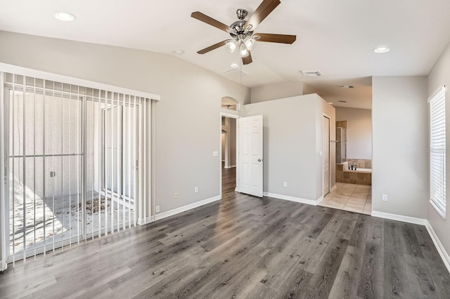 unfurnished bedroom featuring visible vents, lofted ceiling, baseboards, and wood finished floors