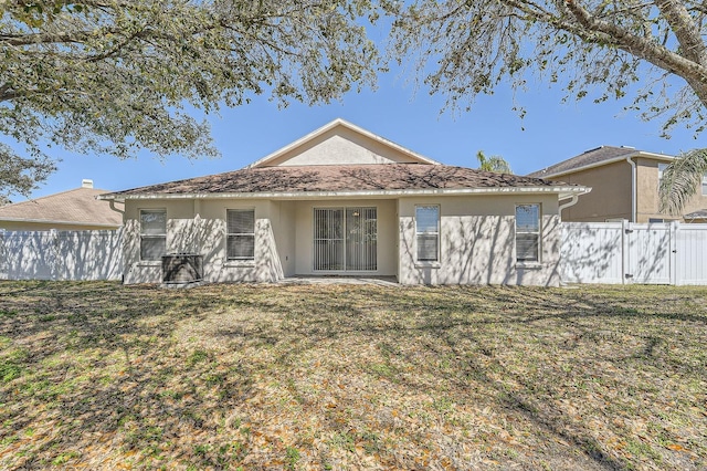 back of property with a yard, fence, and stucco siding