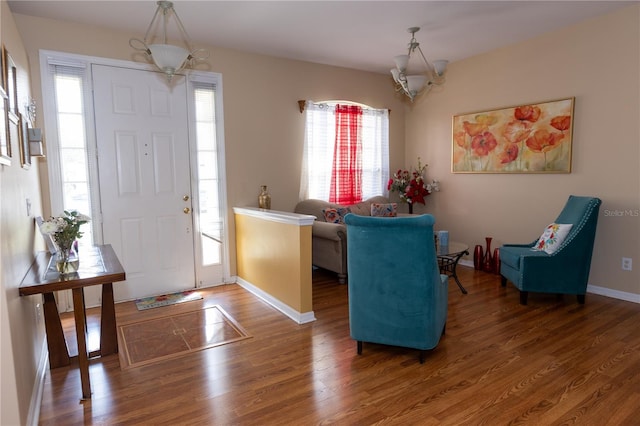 entrance foyer with a notable chandelier, baseboards, and wood finished floors