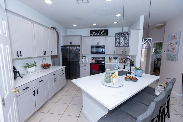 kitchen with black appliances, a sink, recessed lighting, light tile patterned flooring, and hanging light fixtures