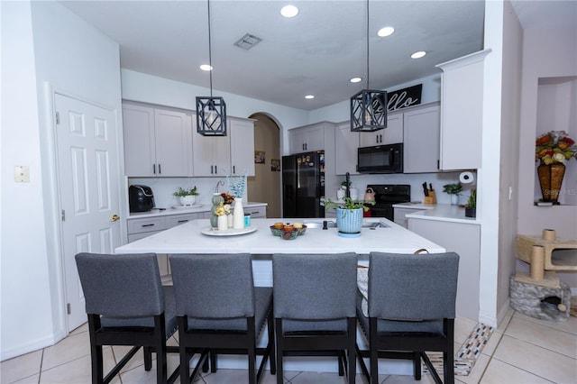 kitchen with visible vents, arched walkways, decorative backsplash, black appliances, and a center island