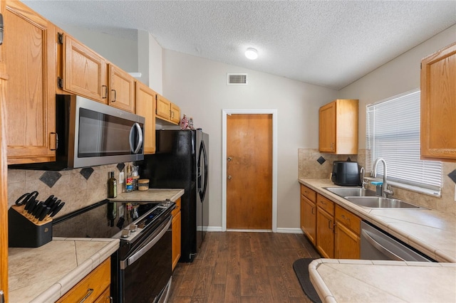 kitchen with visible vents, dark wood-type flooring, lofted ceiling, appliances with stainless steel finishes, and a sink