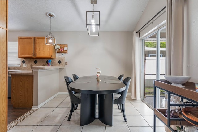 dining room with light tile patterned floors, a textured ceiling, and baseboards