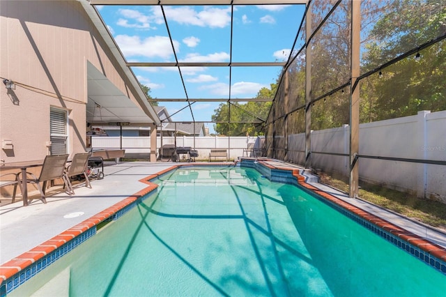 view of pool featuring glass enclosure, a fenced backyard, and a patio area