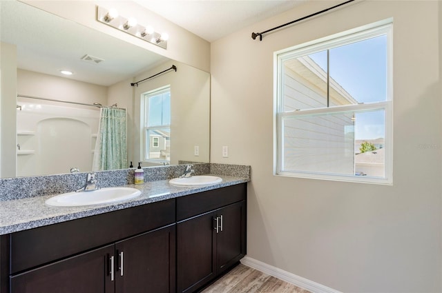 bathroom with baseboards, visible vents, a sink, and wood finished floors