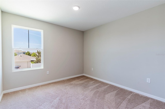 spare room with baseboards and carpet flooring