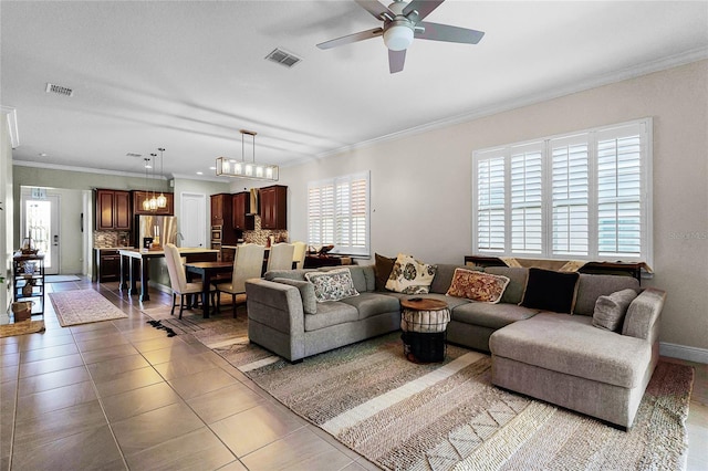 tiled living area featuring baseboards, ceiling fan with notable chandelier, visible vents, and ornamental molding