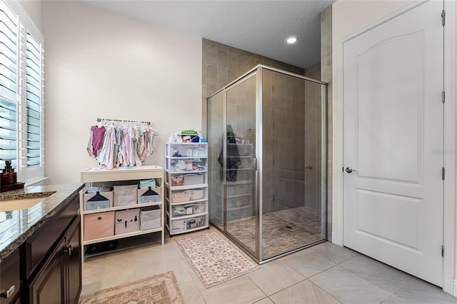 bathroom featuring vanity, a stall shower, tile patterned flooring, and a textured ceiling