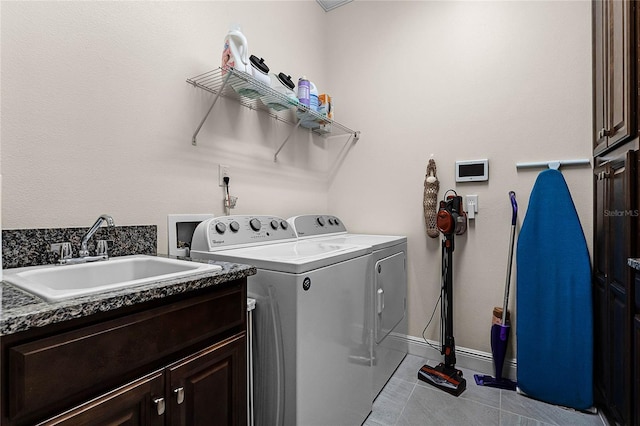 washroom with baseboards, washing machine and clothes dryer, cabinet space, a sink, and tile patterned flooring