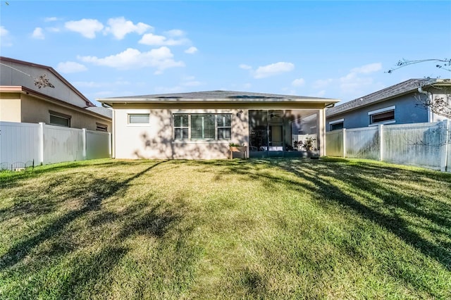 back of house featuring a yard, a fenced backyard, and a sunroom