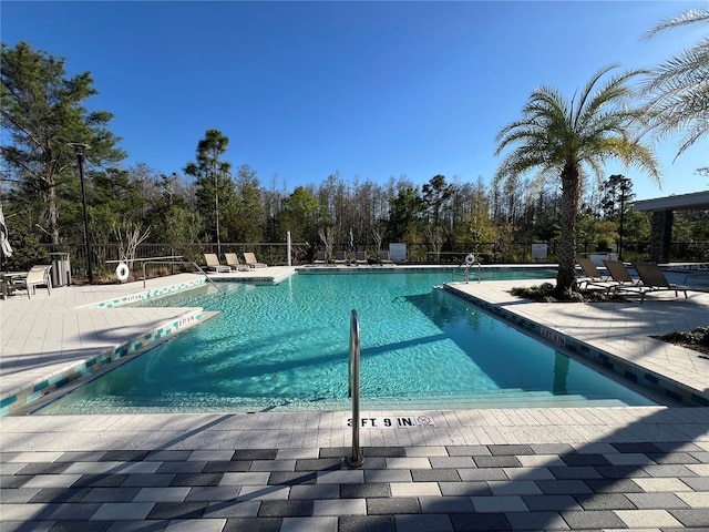 pool with a patio area and fence