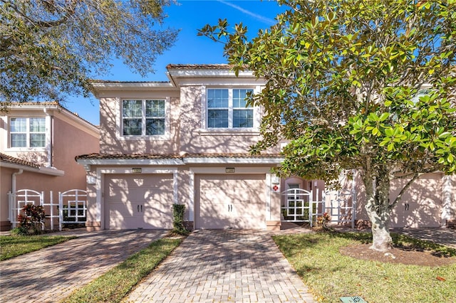 view of front facade featuring an attached garage, fence, stucco siding, driveway, and a gate