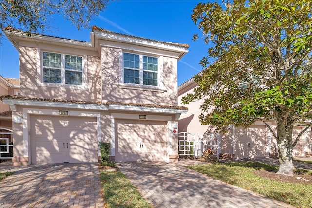 view of front of property with stucco siding, an attached garage, and decorative driveway