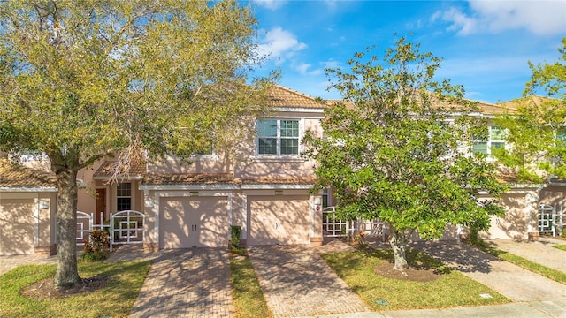 view of front of home with a tile roof, an attached garage, driveway, and stucco siding