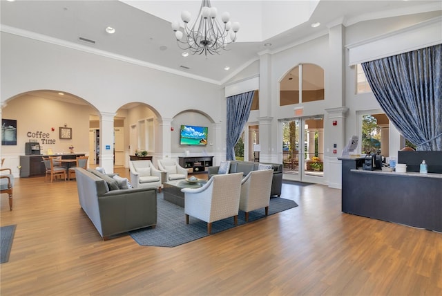 living room with wood finished floors, arched walkways, ornate columns, and ornamental molding