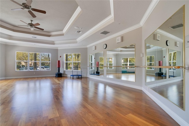 unfurnished living room with a raised ceiling, wood finished floors, and visible vents