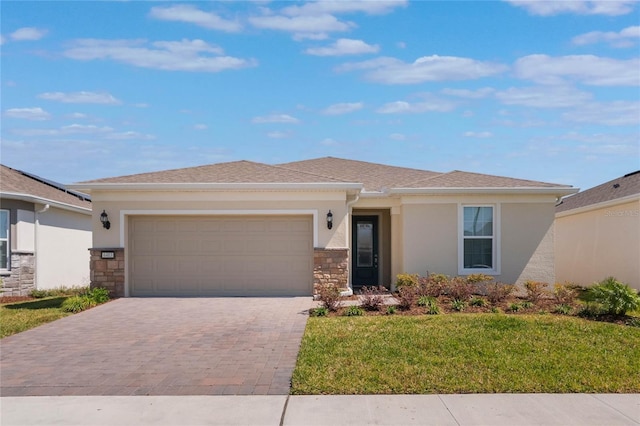 view of front of home featuring stucco siding, a front lawn, a garage, stone siding, and decorative driveway