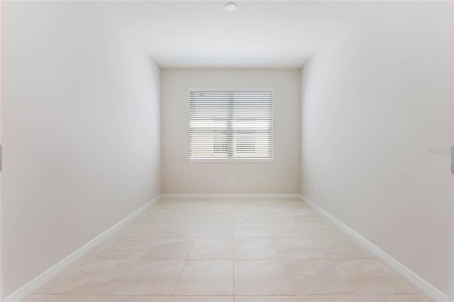 spare room featuring light tile patterned floors and baseboards