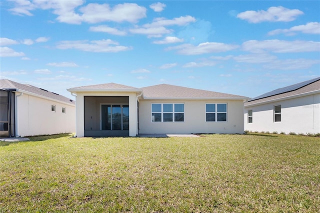 rear view of house featuring a yard and stucco siding