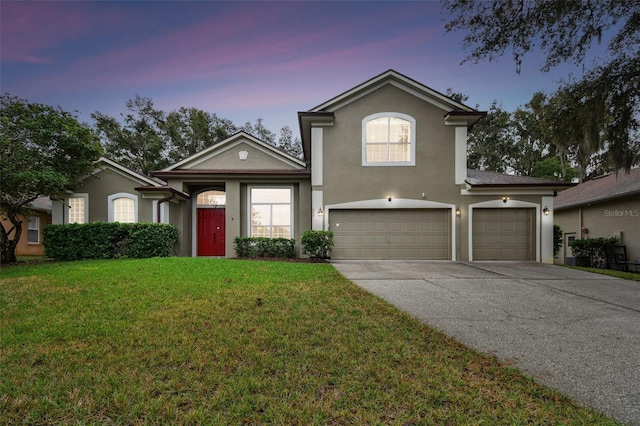 traditional-style home featuring stucco siding, driveway, an attached garage, and a yard