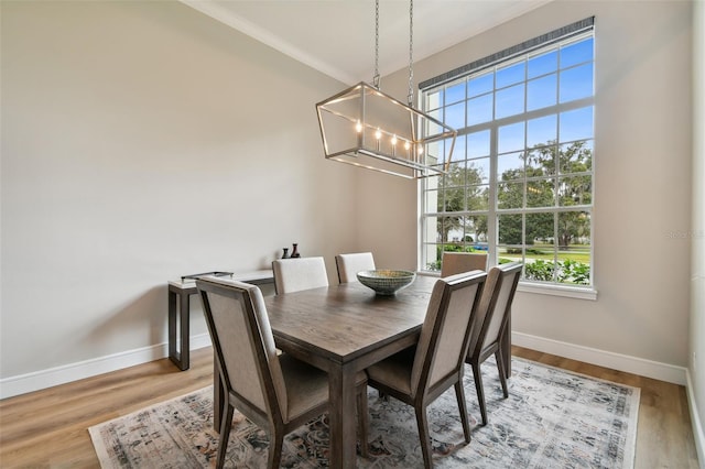 dining area featuring ornamental molding, wood finished floors, baseboards, and a chandelier