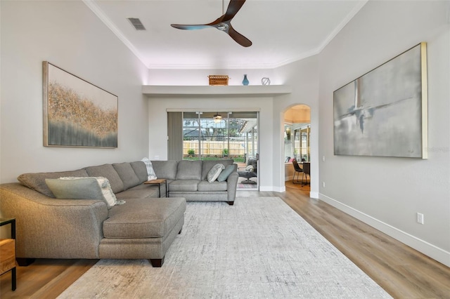 living room featuring visible vents, ornamental molding, a ceiling fan, wood finished floors, and arched walkways