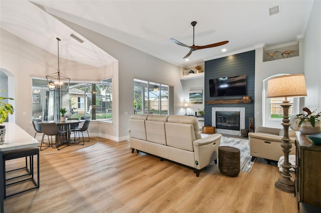 living room featuring visible vents, wood finished floors, a fireplace, and ceiling fan with notable chandelier