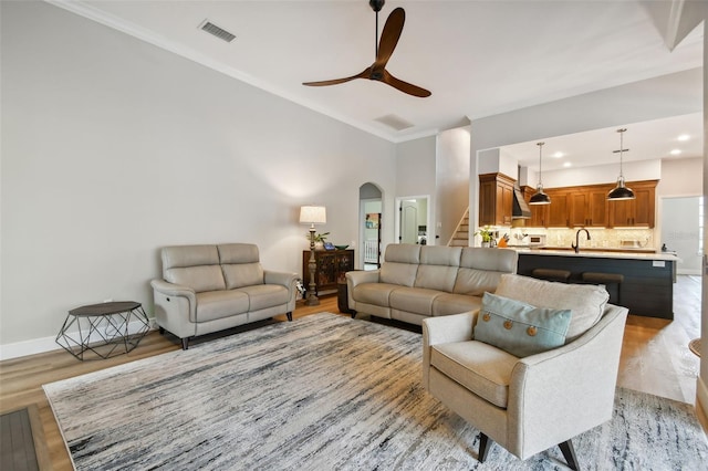 living room featuring stairs, arched walkways, visible vents, and light wood-type flooring